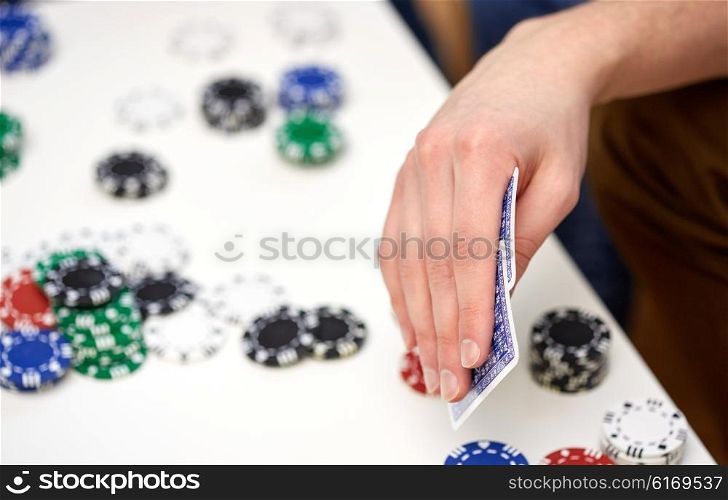 leisure, games, friendship, gambling and entertainment - close up of male hand with playing cards and chips at home
