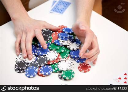 leisure, games, gambling and entertainment - close up of male hands with casino chips and playing cards making bet or taking win at home