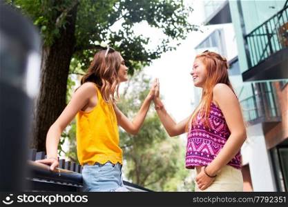 leisure, gesture and friendship concept - happy smiling teenage girls or friends talking on city street in summer. teenage girls or friends talking in summer city