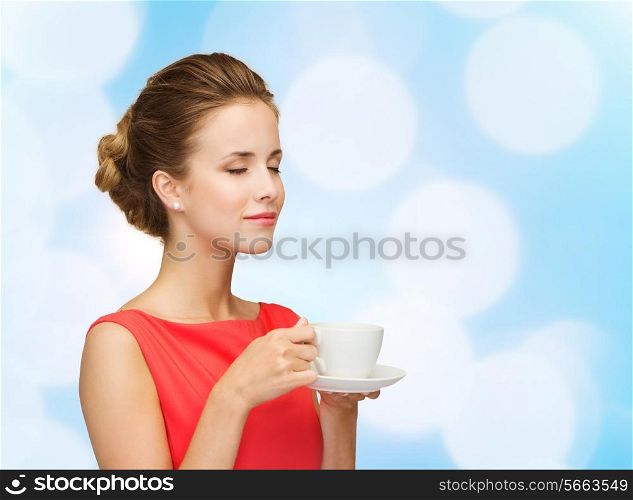 leisure, happiness and drink concept - smiling woman in red dress with cup of coffee over blue lights background