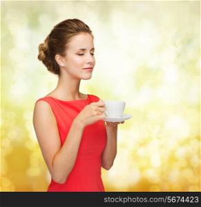 leisure, happiness and drink concept - smiling woman in red dress with closed eyes holding cup of coffee over golden lights background