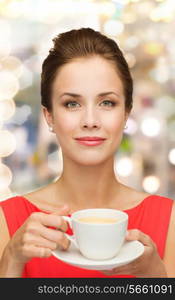 leisure, happiness, holidays and drink concept - smiling woman in red dress with cup of coffee over shiny lights background