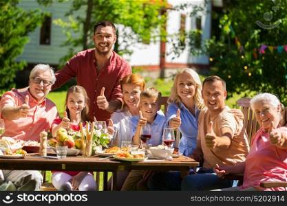 leisure, holidays and people concept - happy family having festive dinner or summer garden party and showing thumbs up. happy family having dinner or summer garden party