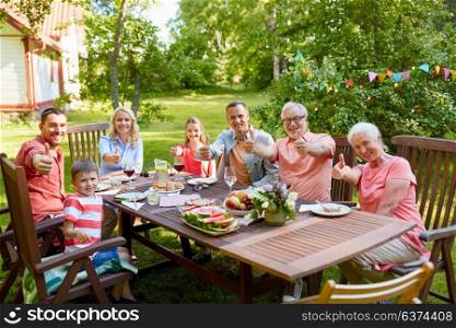 leisure, holidays and people concept - happy family having festive dinner or summer garden party and showing thumbs up. happy family having dinner or summer garden party