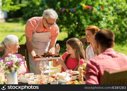 leisure, holidays and people concept - happy family having festive dinner or barbecue party at summer garden. family having dinner or barbecue at summer garden