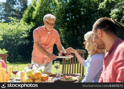 leisure, holidays and people concept - happy family having festive dinner or barbecue party at summer garden. family having dinner or barbecue at summer garden. family having dinner or barbecue at summer garden