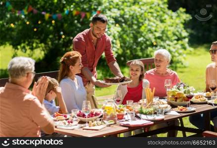 leisure, holidays and people concept - happy family having festive dinner or barbecue party at summer garden. happy family having dinner or summer garden party