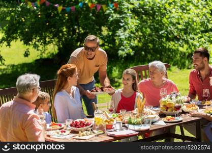 leisure, holidays and people concept - happy family having festive dinner or barbecue party summer garden. happy family having dinner or summer garden party