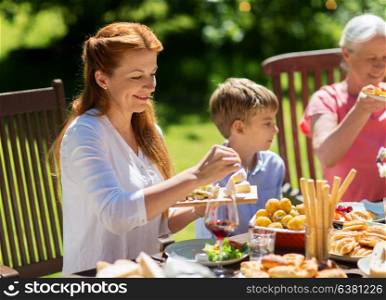 leisure, holidays and people concept - happy family having festive dinner or summer garden party. happy family having dinner or summer garden party