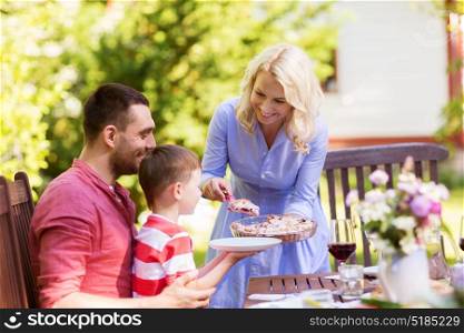 leisure, holidays and people concept - happy family sharing pie at festive dinner or summer garden party. happy family having dinner or summer garden party