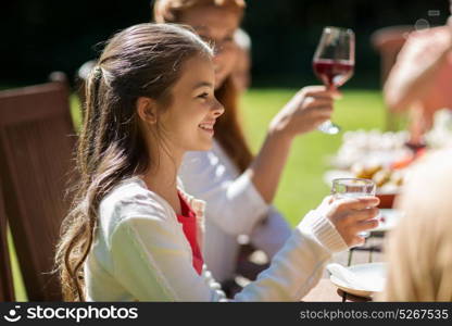 leisure, holidays and people concept - happy girl eating with family at festive dinner or summer garden party. happy girl with family at festive dinner