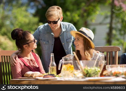 leisure, holidays, communication, people and concept - happy friends having dinner at summer garden party