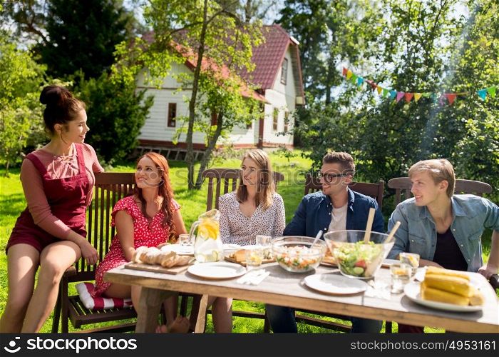 leisure, holidays, communication, people and food concept - happy friends having dinner at summer garden party. happy friends having dinner at summer garden party