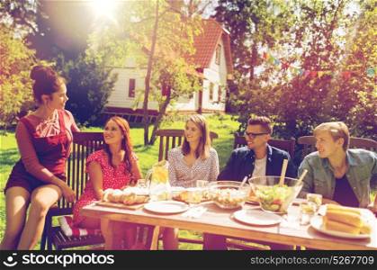 leisure, holidays, communication, people and food concept - happy friends having dinner at summer garden party. happy friends having dinner at summer garden party