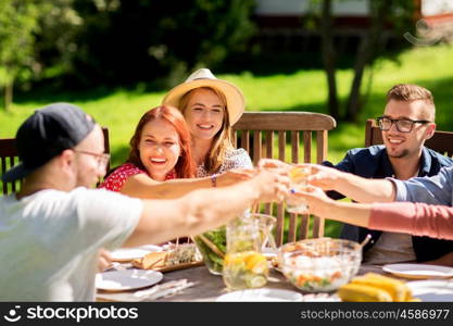 leisure, holidays, eating, people and food concept - happy friends clinking glasses and celebrating at summer garden party