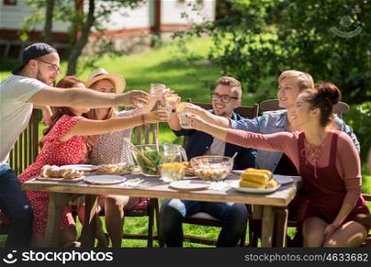 leisure, holidays, eating, people and food concept - happy friends clinking glasses and celebrating at summer garden party