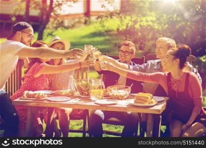 leisure, holidays, eating, people and food concept - happy friends clinking glasses and celebrating at summer garden party. happy friends having dinner at summer garden party