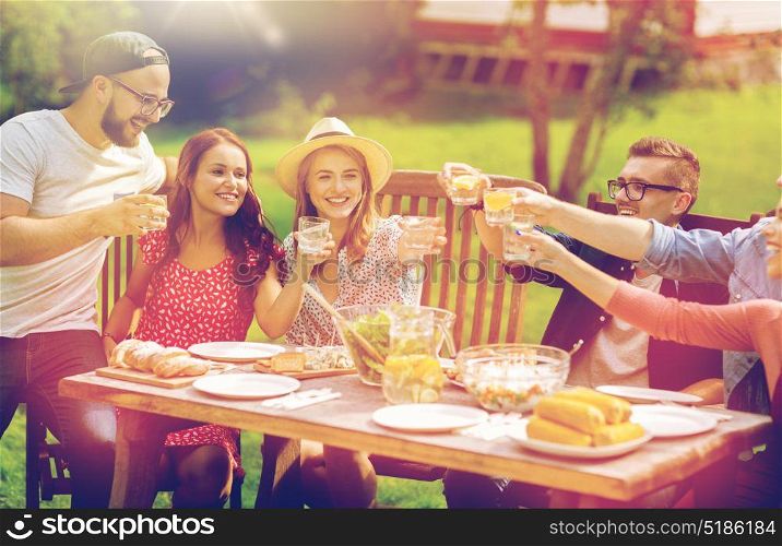 leisure, holidays, eating, people and food concept - happy friends clinking glasses and celebrating at summer garden party. happy friends having dinner at summer garden party