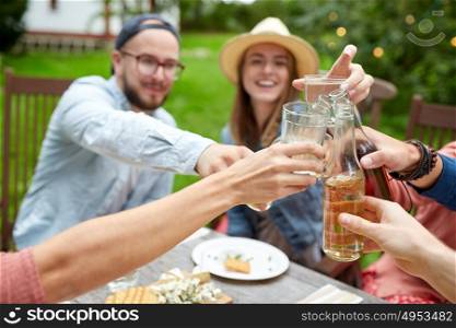 leisure, holidays, eating, people and food concept - happy friends having dinner at summer garden party and clinking drinks. happy friends with drinks at summer garden party