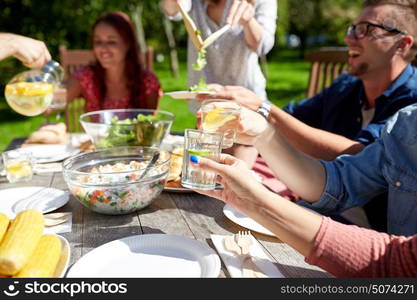 leisure, holidays, eating, people and food concept - happy friends having dinner at summer garden party and clinking drinks. happy friends with drinks at summer garden party