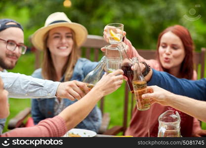 leisure, holidays, eating, people and food concept - happy friends having dinner at summer garden party and clinking drinks. happy friends with drinks at summer garden party