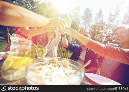 leisure, holidays, eating, people and food concept - happy friends having dinner at summer garden party and clinking drinks. happy friends with drinks at summer garden party