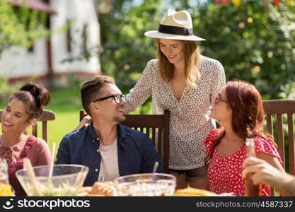 leisure, holidays, eating, people and food concept - happy friends having dinner at summer garden party