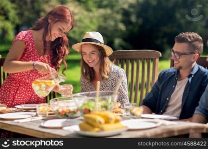 leisure, holidays, eating, people and food concept - happy friends having dinner at summer garden party