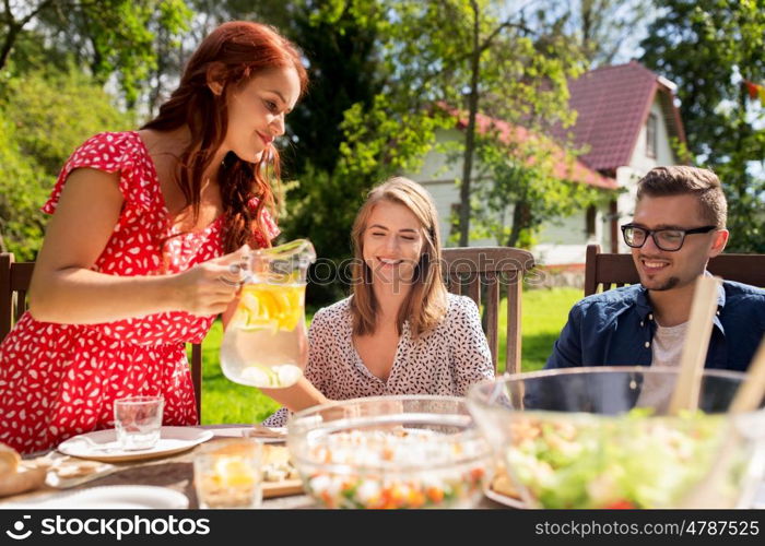 leisure, holidays, eating, people and food concept - happy friends having dinner at summer garden party