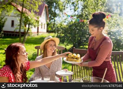 leisure, holidays, eating, people and food concept - happy friends having dinner at summer garden party