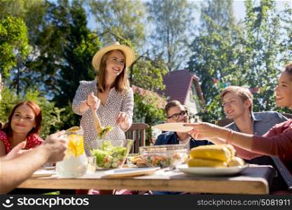 leisure, holidays, eating, people and food concept - happy friends having dinner at summer garden party. happy friends having dinner at summer garden party