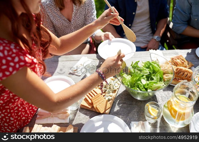 leisure, holidays, eating, people and food concept - happy friends having dinner at summer party. happy friends having dinner at summer party