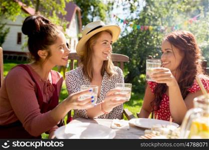 leisure, holidays, eating, people and food concept - happy women or friends with drinks celebrating reunion and having dinner at summer garden party