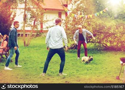 leisure, holidays, people and pets concept - happy friends playing with dog at summer garden party. happy friends playing with dog at summer garden