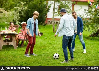 leisure, holidays, people and sport concept - happy friends playing football at summer garden party