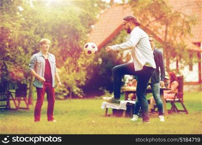 leisure, holidays, people and sport concept - happy friends playing football at summer garden party. happy friends playing football at summer garden
