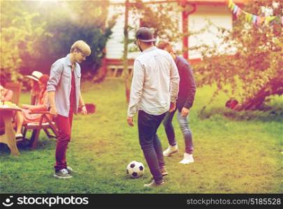 leisure, holidays, people and sport concept - happy friends playing football at summer garden party. happy friends playing football at summer garden