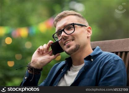 leisure, holidays, people and technology concept - close up of young man calling on smartphone at summer garden party