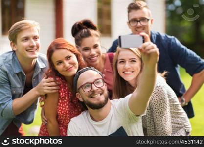 leisure, holidays, reunion, people and friendship concept - happy teenage friends taking selfie by smartphone at summer house