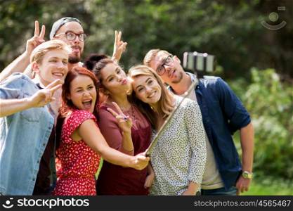 leisure, holidays, reunion, people and friendship concept - happy teenage friends taking picture by smartphone selfie stick at summer