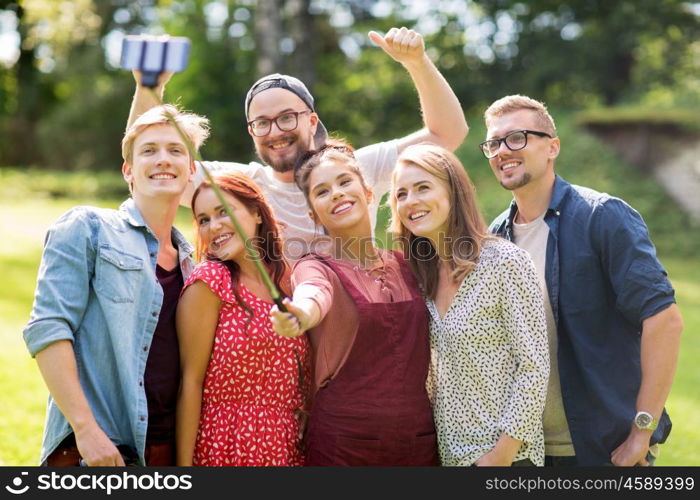 leisure, holidays, reunion, people and friendship concept - happy teenage friends taking picture by smartphone selfie stick at summer