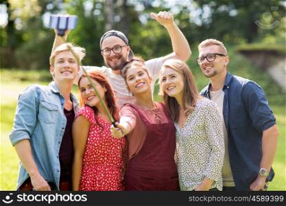 leisure, holidays, reunion, people and friendship concept - happy teenage friends taking picture by smartphone selfie stick at summer