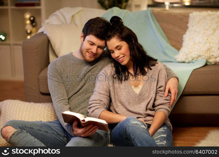 leisure, hygge and people concept - happy couple reading book at home. happy couple reading book at home