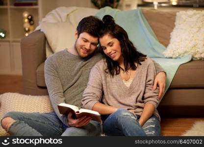 leisure, hygge and people concept - happy couple reading book at home. happy couple reading book at home