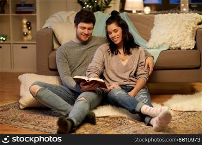 leisure, hygge and people concept - happy couple reading book at home. happy couple reading book at home