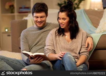 leisure, hygge and people concept - happy couple reading book at home. happy couple reading book at home. happy couple reading book at home