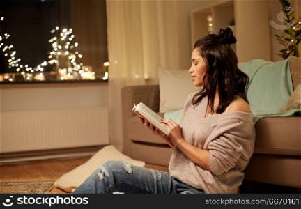 leisure, hygge and people concept - happy young woman reading book at home. happy young woman reading book at home. happy young woman reading book at home