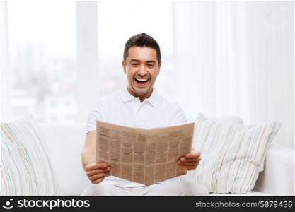 leisure, information, people and mass media concept - happy man reading newspaper and laughing at home