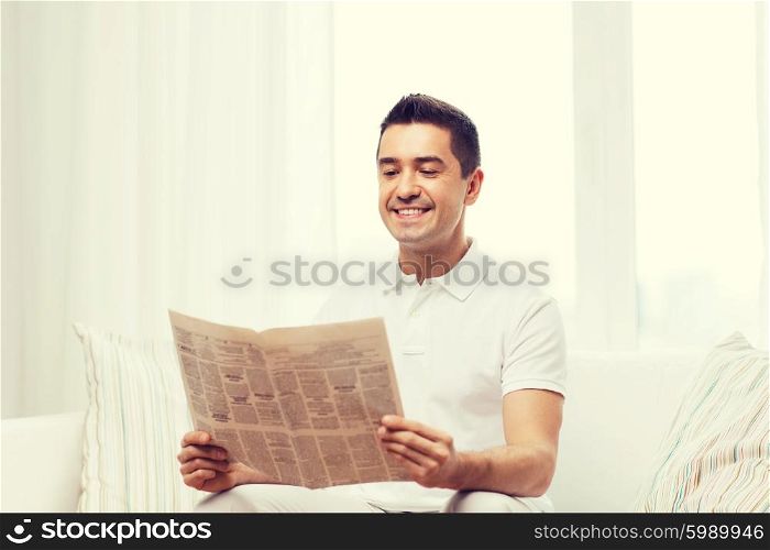 leisure, information, people and mass media concept - happy man reading newspaper at home