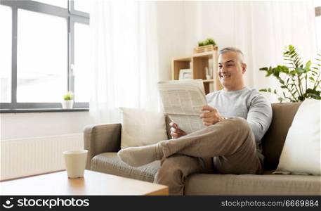 leisure, information, people and mass media concept - happy smiling man reading newspaper at home. happy man reading newspaper at home. happy man reading newspaper at home